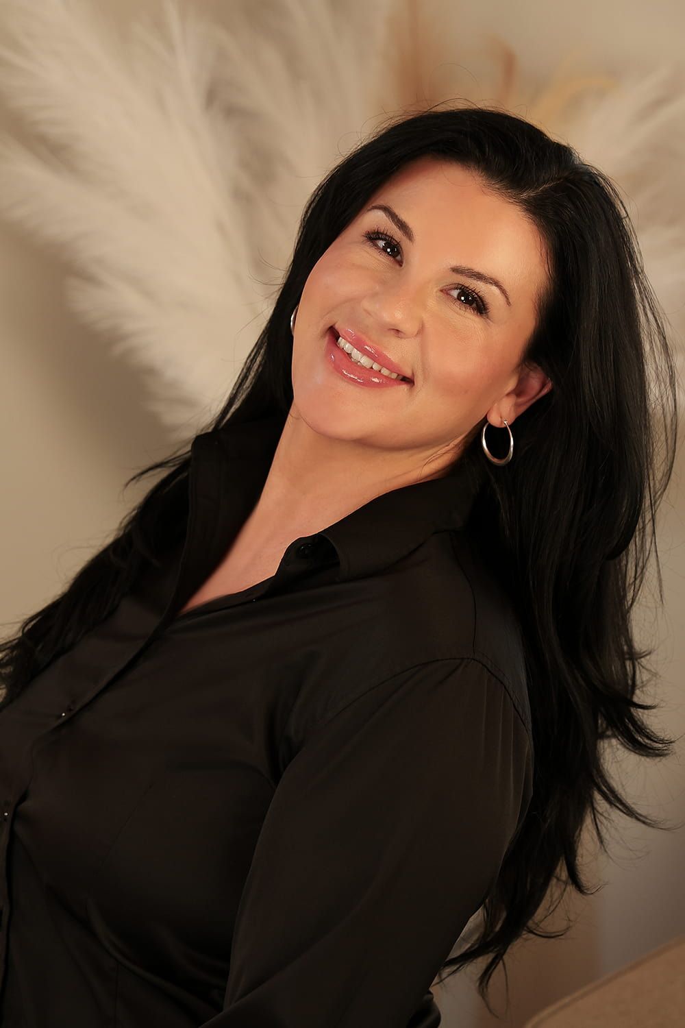 Smiling woman in a black blouse against backdrop.