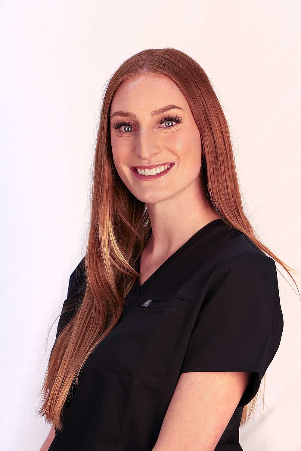 Smiling woman in black medical scrubs.