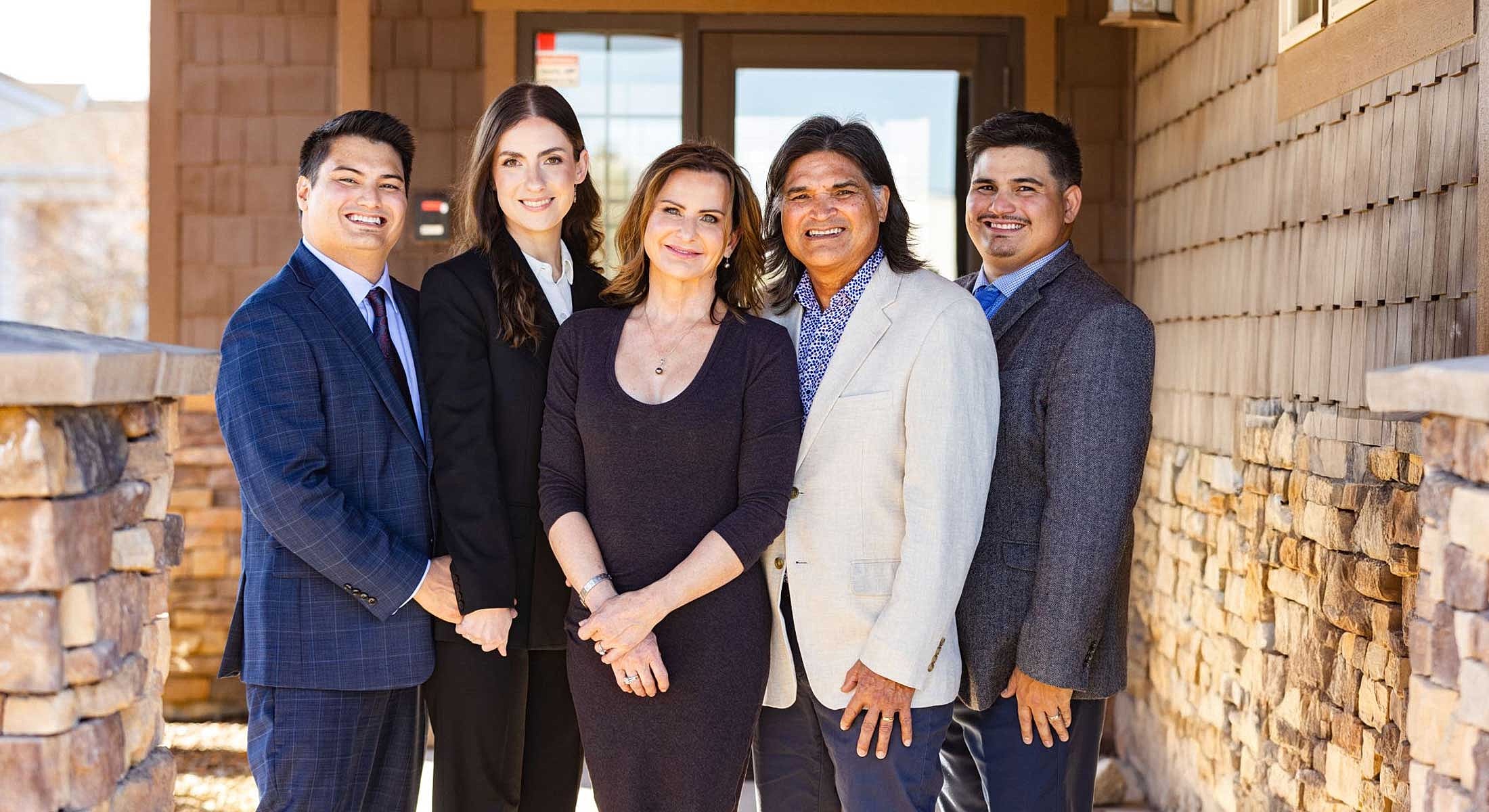 Group of five professionals posing outdoors.